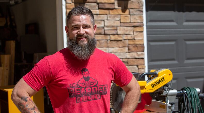 Tony Rissley stands outside is Sugar Hill home. Tony's auction business took a bit hit with the pandemic and he knew he'd have to find another way to bring in money. He'd always had an interest in handiwork, so he took advantage of the free time, learned many new skills, and had plenty (very funny) "fake it till you make it" experiences when he launched a new business, Tony the Bearded Builder. He's tackled an array of building projects, inside and outside of homes, and maintains a fully booked calendar. The mid-pandemic leap of faith was worth it. PHIL SKINNER FOR THE ATLANTA JOURNAL-CONSTITUTION.