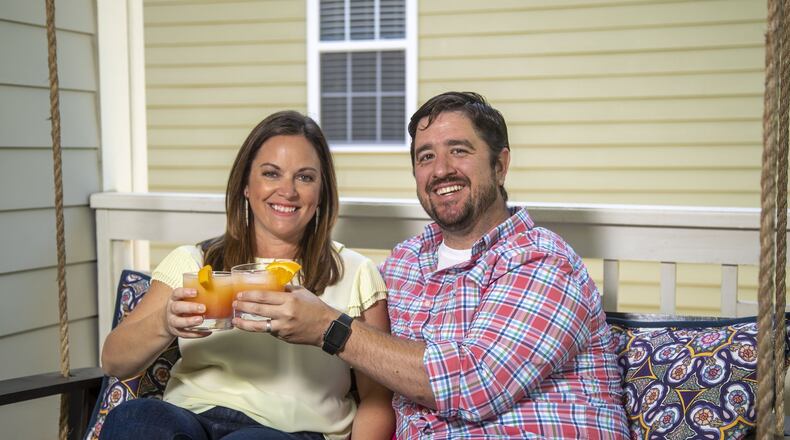 Heather and Kevin Freaney have been creating cocktails on an almost nightly basis since the COVID-19 pandemic has affected their lives. They are holding a Malibu Sunset cocktail. (ALYSSA POINTER / ALYSSA.POINTER@AJC.COM)