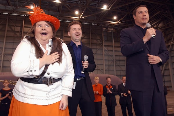 Australian actor Magda Szubanski, left, mocks her desire for American movie star John Travolta, right, during the unveiling of airline Jet Star's first plane in Sydney, May 10, 2004. (AP Photo/Rick Rycroft, File)