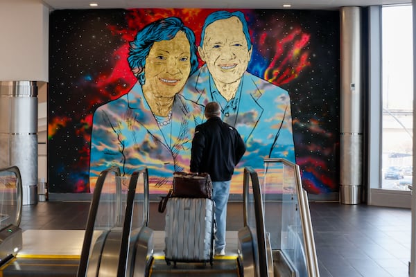A traveler looks at a mural of Jimmy and Rosalynn Carter at Hartsfield-Jackson Atlanta International Airport. The airport is a topic of discussion on today's "Politically Georgia" podcast.