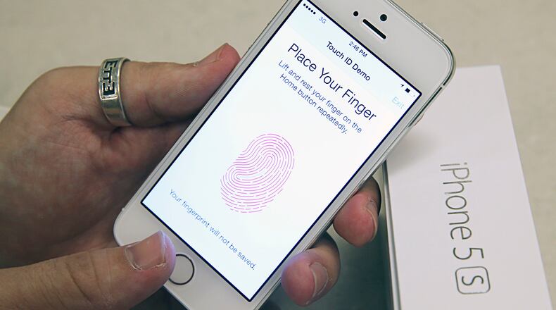 An employee tests the fingerprint scanner on the new Apple iPhone 5S at a Verizon store in Orem, Utah September 19, 2013. The iPhone 5C, which comes in blue, green, pink, yellow and white, starts in the U.S. at $99 with a contract and the pricier "5S" begins at $199 with a contract. Both models go on sale in several countries on September 20.