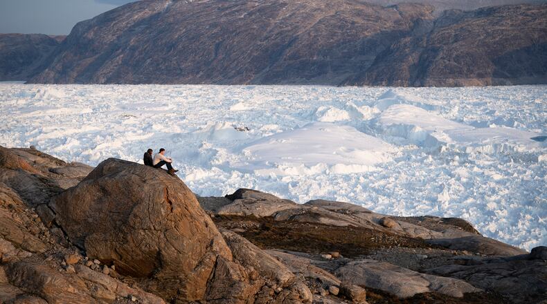 FILE - NYU student researchers sit on top of a rock overlooking the Helheim glacier in Greenland, Aug. 16, 2019. (AP Photo/Felipe Dana, File)