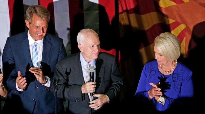 Sen. John McCain, R-Ariz., middle, pauses as he talks to supporters after being declared the winner in the Arizona Republican primary, as his wife Cindy McCain, right, and Sen. Jeff Flake, R-Ariz., left, join him on stage Tuesday, Aug. 30, 2016, in Phoenix. The 80-year-old McCain defeated former state Sen. Kelli Ward and two other Republicans on the ballot. (AP Photo/Ross D. Franklin)