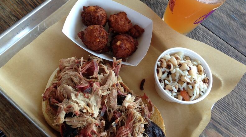 Pulled pork, Hoppin' John, hush puppies and a cold beer from Southern Soul Barbeque in St. Simons. / SUZANNE VAN ATTEN / SVANATTEN@AJC.COM