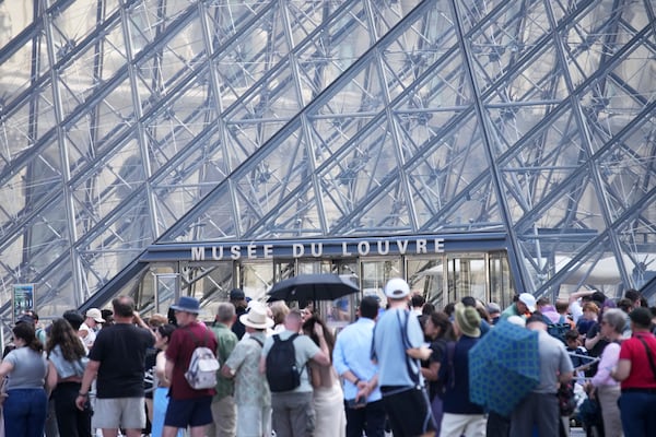 Tourists wait outside the Louvre museum which failed to open on time Monday, June 16, 2025 in Paris. (AP Photo/Christophe Ena)