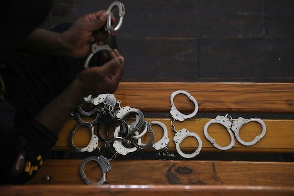 A police officer holds up the handcuffs removed from Colombians and Haitians accused of involvement in the 2021 assassination of Haitian President Jovenel Moise, in court in Port-au-Prince, Haiti, Monday, June 2, 2025. (AP Photo/Odelyn Joseph)