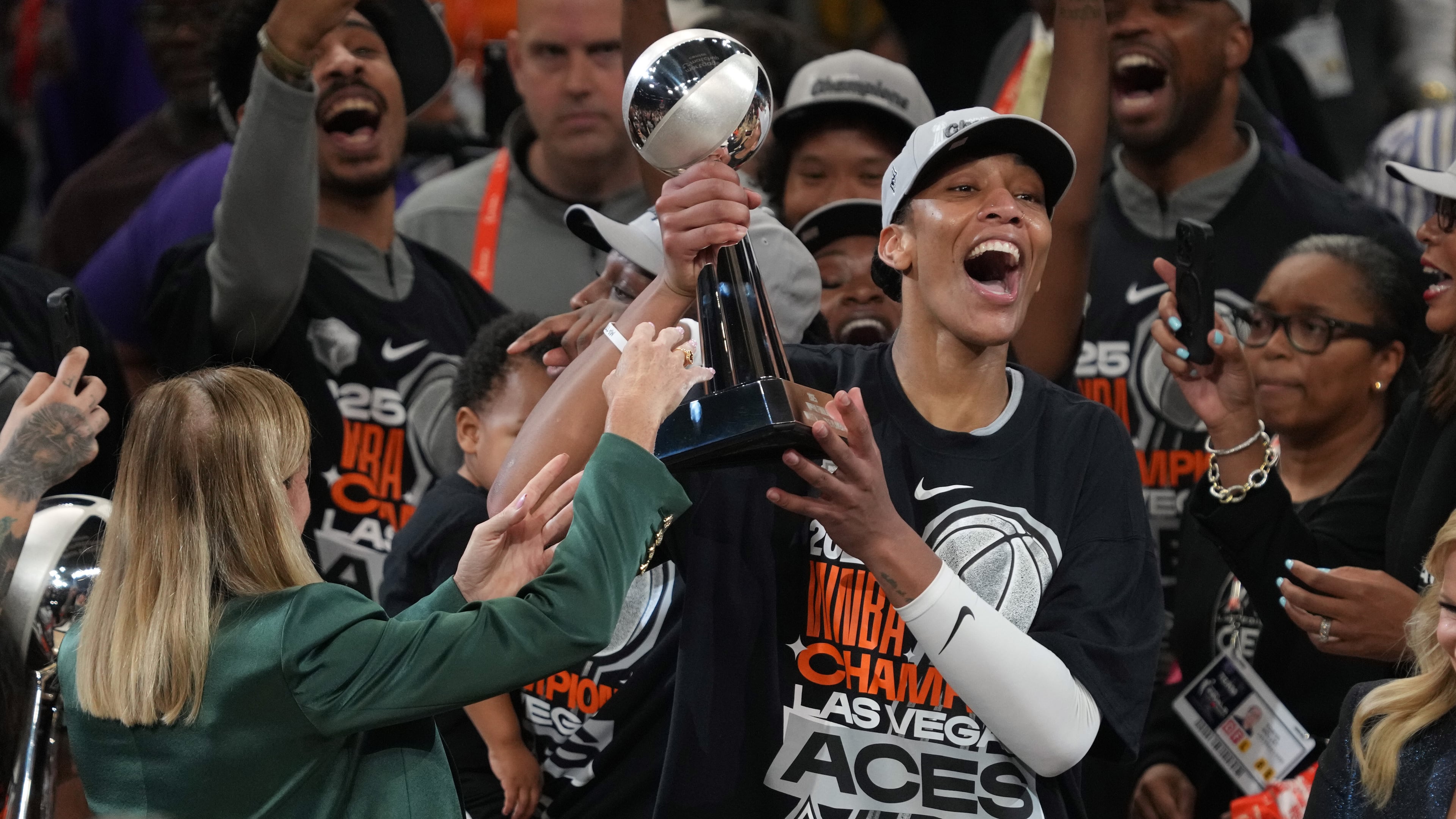 Las Vegas Aces center A'ja Wilson, center right, holds up her MVP trophy after Game 4 of the WNBA basketball finals against the Phoenix Mercury, Friday, Oct. 10, 2025, in Phoenix. (AP Photo/Rick Scuteri)