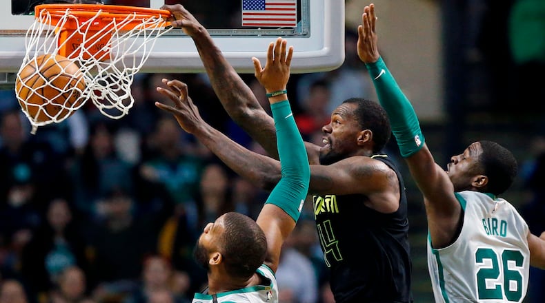 Atlanta Hawks' Dewayne Dedmon (14) dunks against Boston Celtics' Greg Monroe, left, and Jabari Bird (26) during the fourth quarter Sunday, April 8, 2018, in Boston.