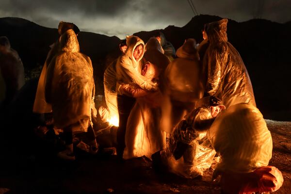 This image provided by World Press Photo and taken by John Moore, Getty Images, was one of two runners-up for the World Press Photo Award of the Year and shows Chinese migrants warm themselves under a cold rain after crossing the US–Mexico border, Campo, California, March 7, 2024. (John Moore, Getty Images/World Press Photo via AP)