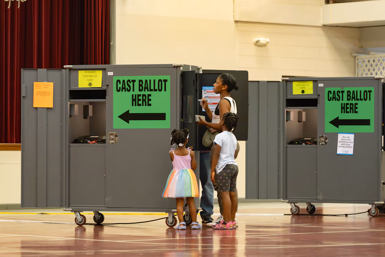A woman votes while her children watch at the Floyd Road Baptist Church polling location on Tuesday, May 19, 2026, in Austell. (Ben Hendren for the AJC)