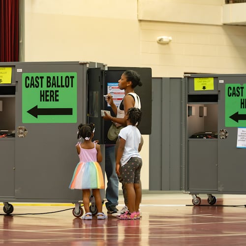 A woman votes while her children watch at the Floyd Road Babtist Church polling location in Austell, Georgia. Tuesday, May 19, 2026 (Ben Hendren for the AJC)
