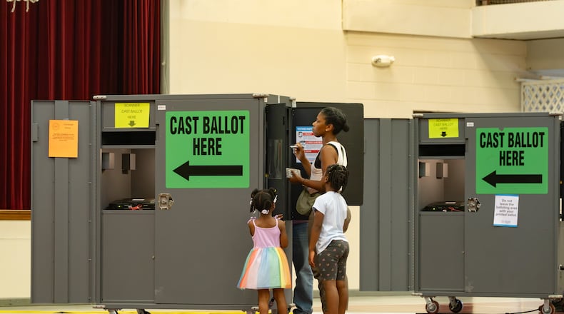 A woman votes while her children watch at the Floyd Road Babtist Church polling location in Austell, Georgia. Tuesday, May 19, 2026 (Ben Hendren for the AJC)