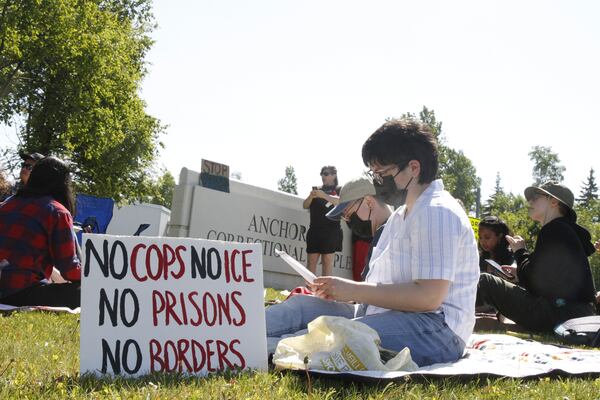 Demonstrators sit on the lawn of the Anchorage Correctional Complex Thursday, June 12, 2025, in Anchorage, Alaska, to protest the detainment of about 40 people being held there under the custody of the Immigration and Customs Enforcement federal agency. (AP Photo/Mark Thiessen)