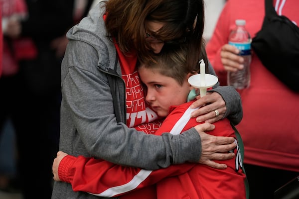 Teacher Dawn Peck hugs her seven-year-old student Harriet Glessner at a vigil for three young children and a teenager who were killed when a car barreled through a building used for an after-school camp Tuesday, April 29, 2025, in Chatham, Ill. (AP Photo/Erin Hooley)