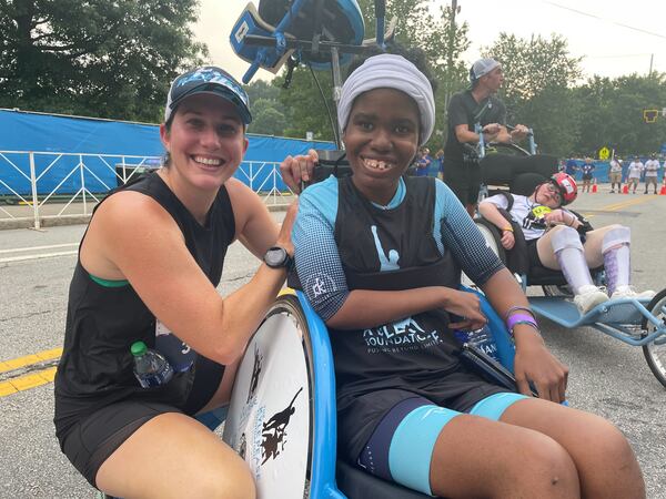 Wheelchair participant Brandi Thomas and accompanying runner Meghan Degan at the Atlanta Journal-Constitution Peachtree Road Race in Atlanta on Monday, July 4, 2022.