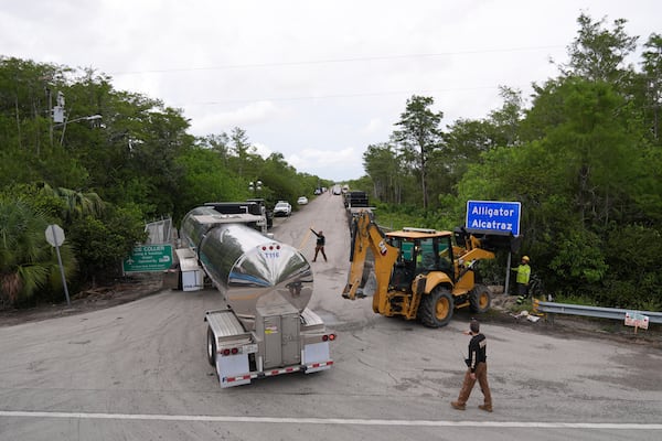Workers install a sign reading "Alligator Alcatraz" at the entrance to a new migrant detention facility at Dade-Collier Training and Transition facility, Thursday, July 3, 2025, in Ochopee, Fla. (AP Photo/Rebecca Blackwell)