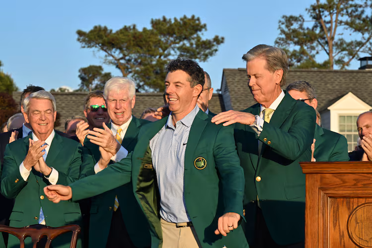 Fred S. Ridley, Chairman of Augusta National Golf Club and the Masters, places the green jacket on 2026 winner Rory McIlroy at Augusta National on Sunday, April 12, 2026, in Augusta, Ga. (Hyosub Shin/AJC)