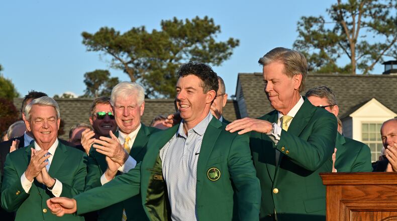 Fred S. Ridley, chairman of Augusta National Golf Club and the Masters, places the green jacket on 2026 winner Rory McIlroy at Augusta National on Sunday, April 12, 2026, in Augusta, Ga. (Hyosub Shin/AJC)