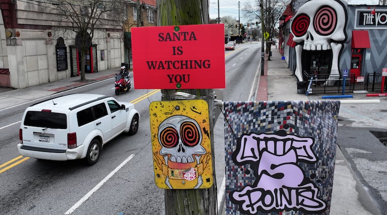 Cars pass by a sign that reads "SANTA IS WATCHING YOU" on a utility pole on Moreland Avenue near the Vortex Bar and Grill in Little Five Points, Atlanta, Tuesday, March 10, 2026. (Hyosub Shin/AJC)