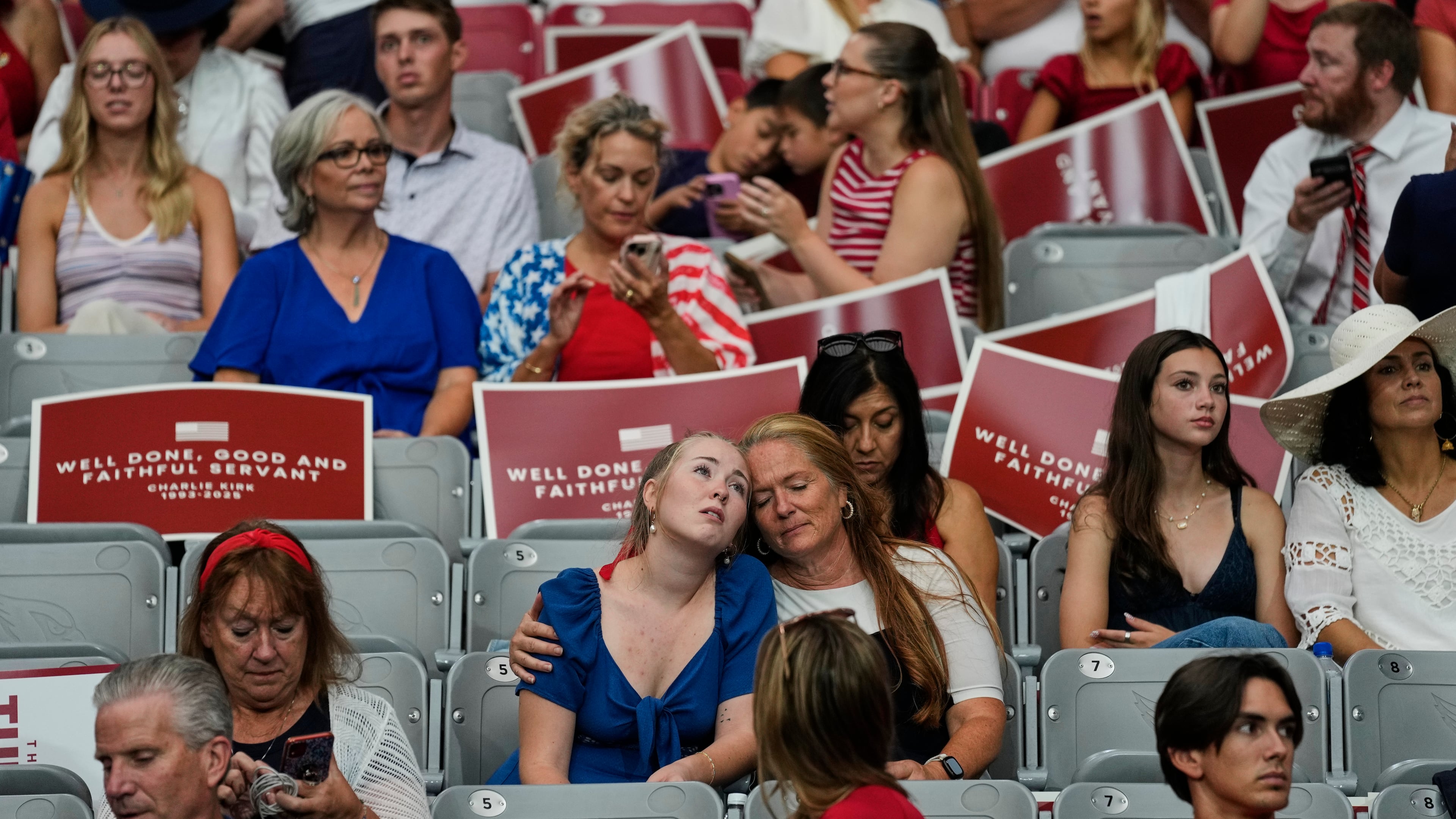 People sit inside before the start of a memorial for conservative activist Charlie Kirk, Sunday, Sept. 21, 2025, at State Farm Stadium in Glendale, Ariz. (AP Photo/John Locher)