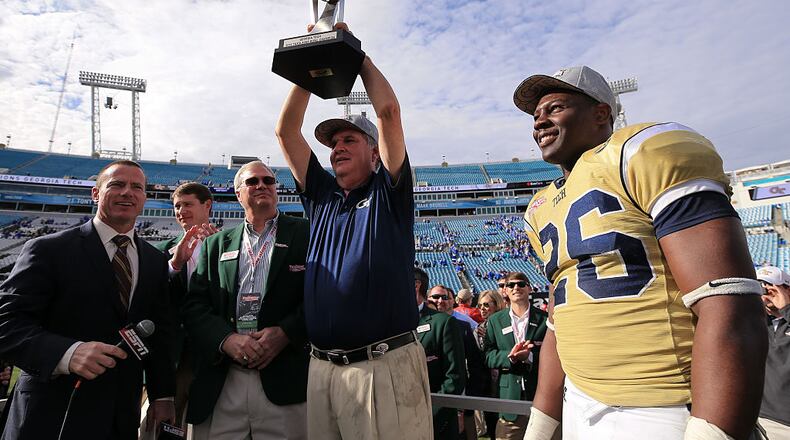 Head coach Paul Johnson of the Georgia Tech Yellow Jackets hoists the TaxSlayer Bowl trophy as Dedrick Mills #26 looks on after the game against the Kentucky Wildcats at EverBank Field on December 31, 2016 in Jacksonville, Florida. (Photo by Rob Foldy/Getty Images)