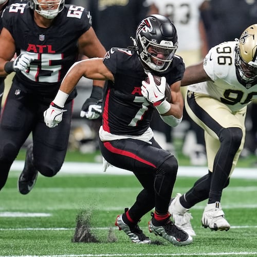 Atlanta Falcons running back Bijan Robinson (left) carries past New Orleans Saints defensive end Carl Granderson in the first half of an NFL game, Sunday, Jan. 4, 2026, in Atlanta. (Mike Stewart/AP)
