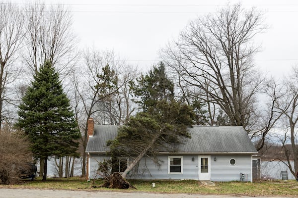 An uprooted tree leans on a home after a severe storm hit Sunday along Clear Lake in Barry County, Mich., on Monday, March 31, 2025. (Joel Bissell/MLive.com/Kalamazoo Gazette via AP)