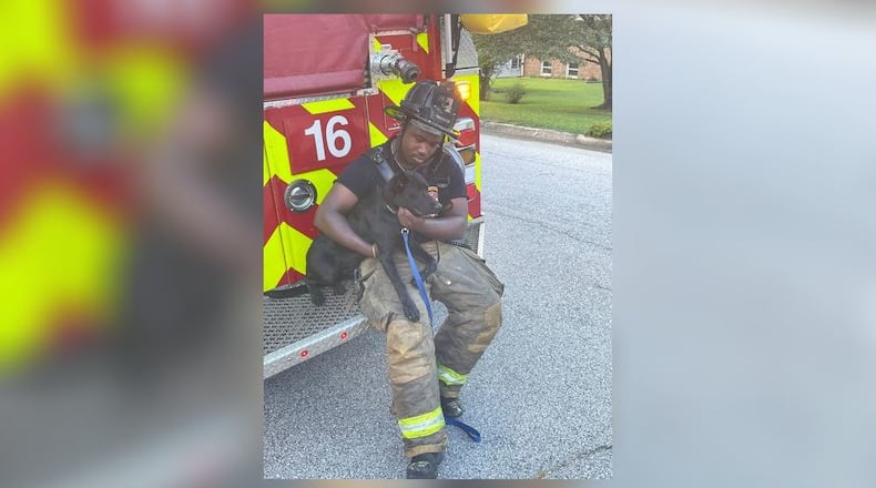 DeKalb County firefighter Darius Crowder and his 6-month-old puppy Xina embrace after he found her safe from a house fire Wednesday afternoon. Three dogs died in the blaze.