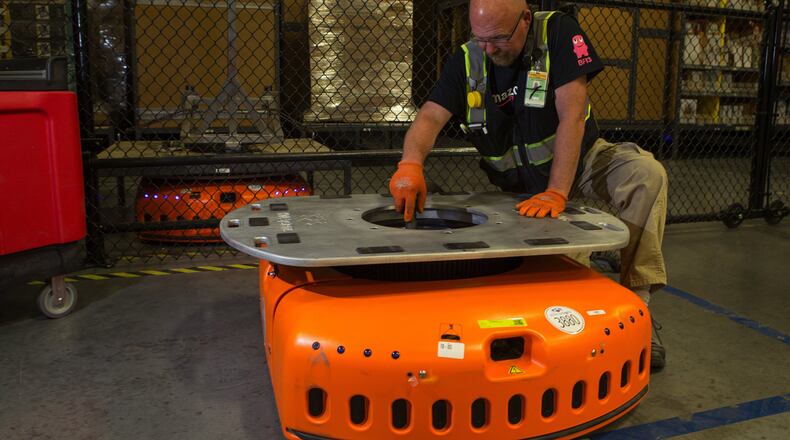Barry Tormoehlen, a maintenance technician at Amazon’s fulfillment center in DuPont, vacuums the inside of a KIVA, one of Amazon’s robots that are used to move items around the center, Monday, July 3, 2017. The KIVAs weigh 800 pounds each and can carry up to 3,000 pounds of merchandise. (Ellen M. Banner/Seattle Times/TNS)