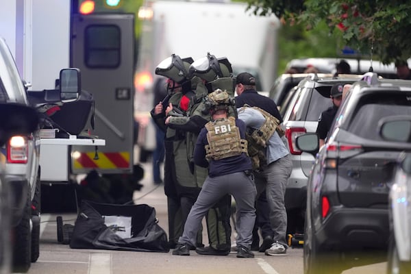Law enforcement officials dress in protective gear to investigate after an attack on the Peark Street Mall Sunday, June 1, 2025, in Boulder, Colo. (AP Photo/David Zalubowski)