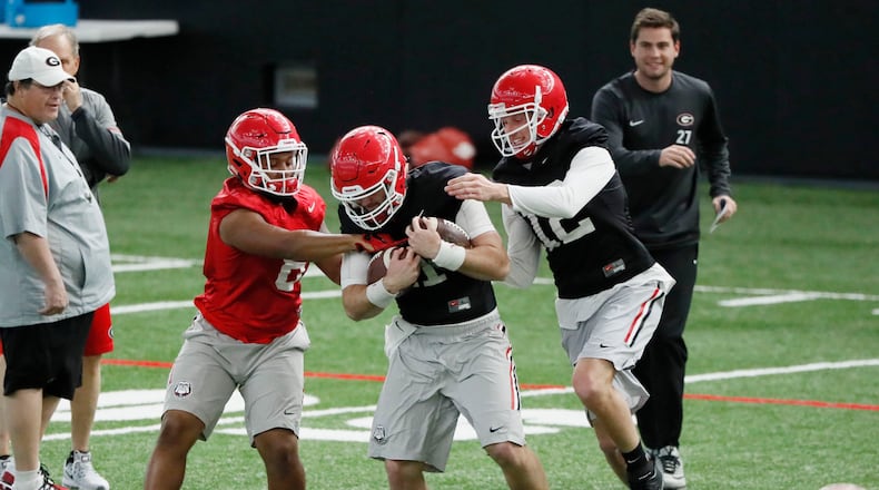 Georgia players, including  quarterback Jake Fromm (11) (with balls) during drills at practice today. Georgia traveled back to its indoor facilities in Athens two days before the national title game against Alabama in January. The indoor facility is expected to be named after former UGA player and Augusta National chairman Billy Payne.