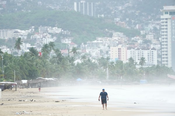 A tourist walks on Manzanillo beach as Hurricane Erick passes near Acapulco, Mexico, Thursday, June 19, 2025. (AP Photo/Fernando Llano)