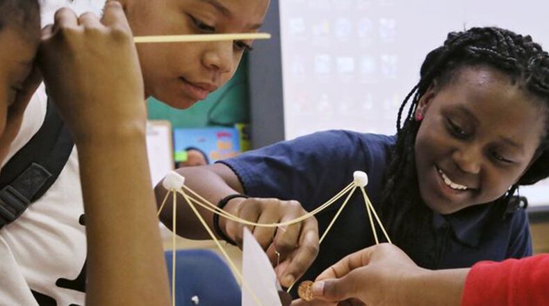 Za Riyah Jones (left) and Laryssa Brogdon use pennies to test the load-bearing capacity of a bridge they built with spaghetti and marshmallows in a gifted class at Chapel Hill Elementary School in DeKalb.