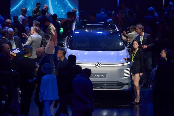 Attendees look at the latest cars from Volkswagen Group during the media night ahead of the Auto Show in Shanghai, Tuesday, April 22, 2025. (AP Photo/Ng Han Guan)
