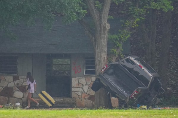 A person pulls luggage at Camp Mystic along the banks of the Guadalupe River after a flash flood swept through the area Sunday, July 6, 2025, in Hunt, Texas. (AP Photo/Julio Cortez)