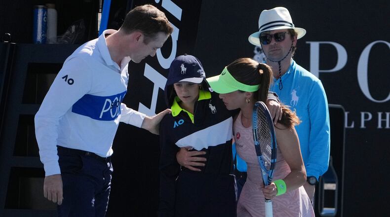 Zeynep Sonmez of Turkey and umpire Chase Urban help a ball kid who fainted, from the court during her first round match against Ekaterina Alexandrova of Russia at the Australian Open tennis championship in Melbourne, Australia, Sunday, Jan. 18, 2026. (AP Photo/Asanka Brendon Ratnayake)