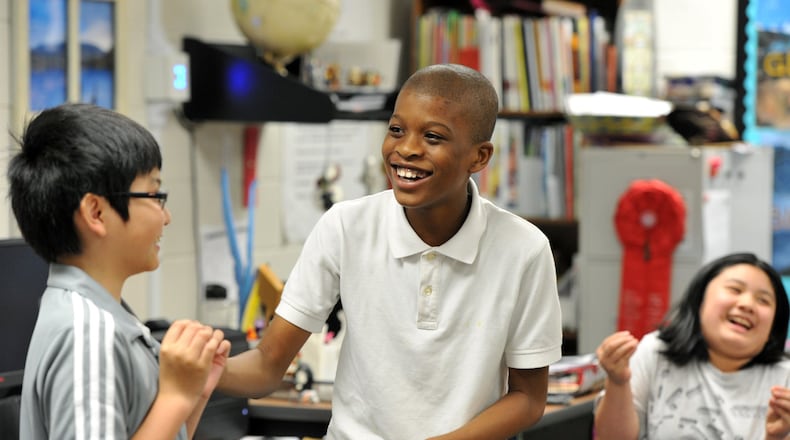 Stanley Udekigbo (center), 11, shares a laugh with Ryan Mai (left), 10, as they rehearse for “Shakespeare’s Hamlet for kids” in a 5th grade gifted class at Lilburn Elementary School in this 2014 file photo.