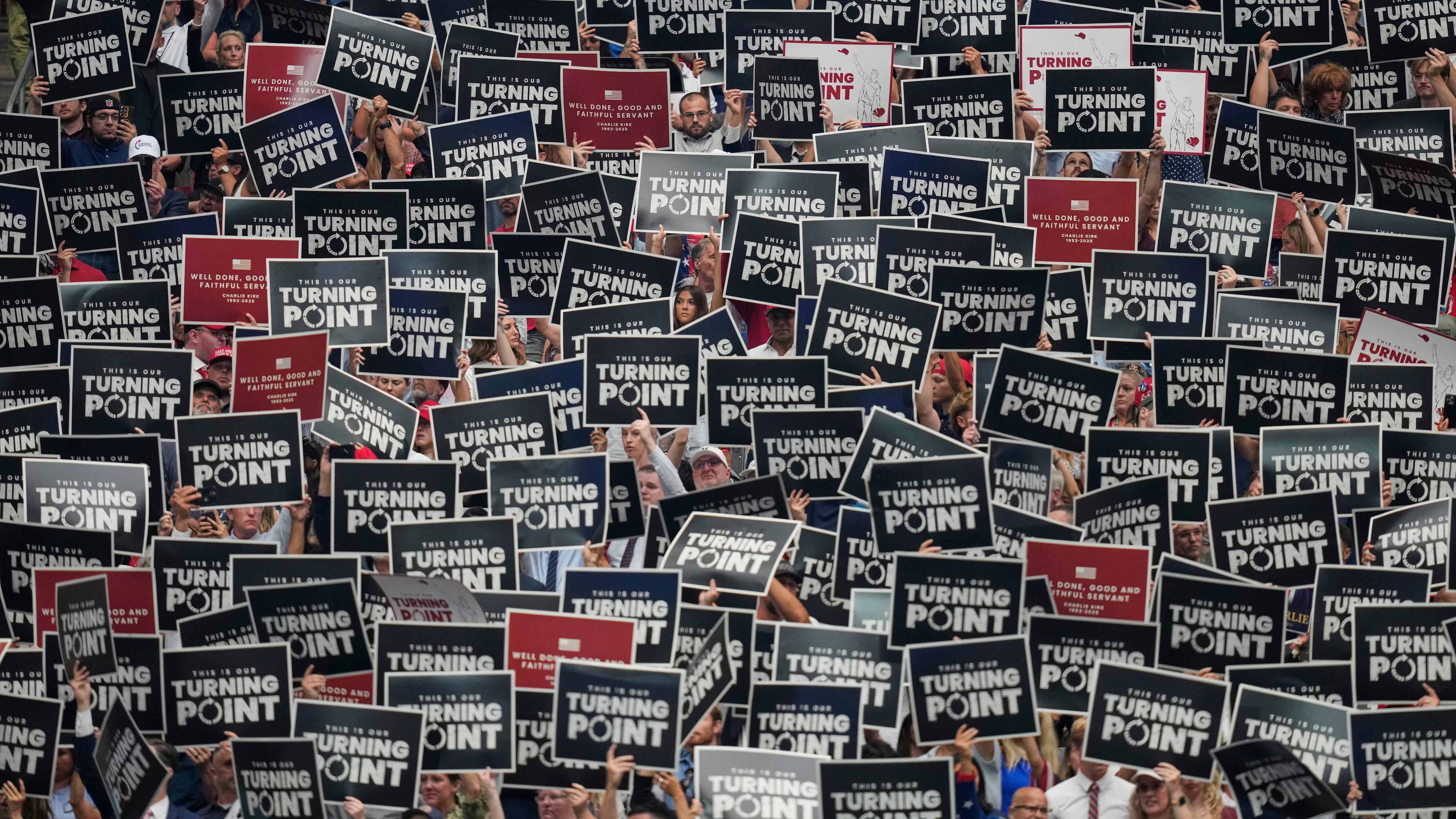 People hold up signs during a memorial for conservative activist Charlie Kirk, Sunday, Sept. 21, 2025, at State Farm Stadium in Glendale, Ariz. (AP Photo/John Locher)