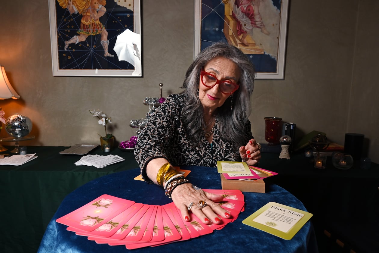 Healing practitioner Rolene Jaffe shows Rise & Radiate oracle cards, which Jaffe created, at 7th House, an astrological-themed restaurant where her son, Alexander Sher, is part owner, on Wednesday, April 1, 2026, in Atlanta. (Hyosub Shin/AJC)