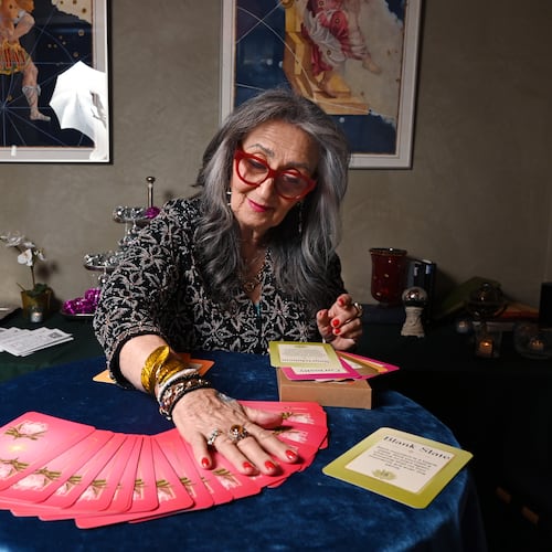Healing practitioner Rolene Jaffe shows Rise & Radiate oracle cards, which Jaffe created, at 7th House, an astrological-themed restaurant where her son, Alexander Sher, is part owner, on Wednesday, April 1, 2026, in Atlanta. (Hyosub Shin/AJC)