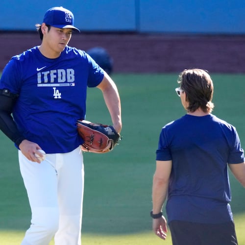 Los Angeles Dodgers' Shohei Ohtani warms up with a trainer prior to a baseball game against the Pittsburgh Pirates, Friday, Aug. 21, 2026, in Los Angeles. (AP Photo/Mark J. Terrill)