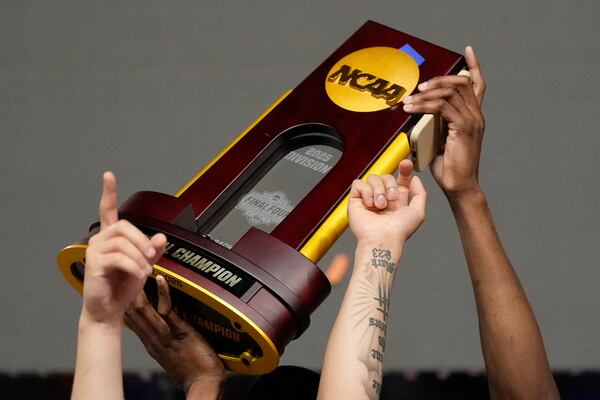 Florida men's basketball players hold up the NCAA Tournament championship trophy after beating Houston on Monday night.