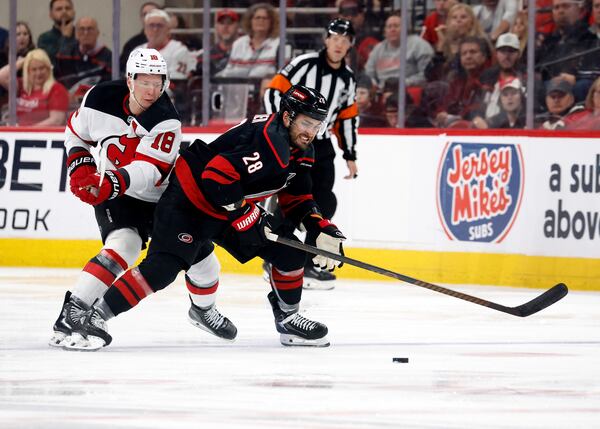 Carolina Hurricanes' William Carrier (28) tries to move the puck away from New Jersey Devils' Ondrej Palat (18) during the first overtime period of Game 5 of an NHL hockey Stanley Cup first-round playoff series in Raleigh, N.C., Tuesday, April 29, 2025. (AP Photo/Karl DeBlaker)