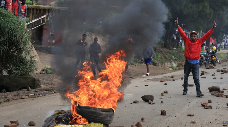 A man demonstrates near a fire during a public transport strike over fuel prices in Nairobi, Kenya, Monday, May 18, 2026. (AP Photo/Andrew Kasuku)