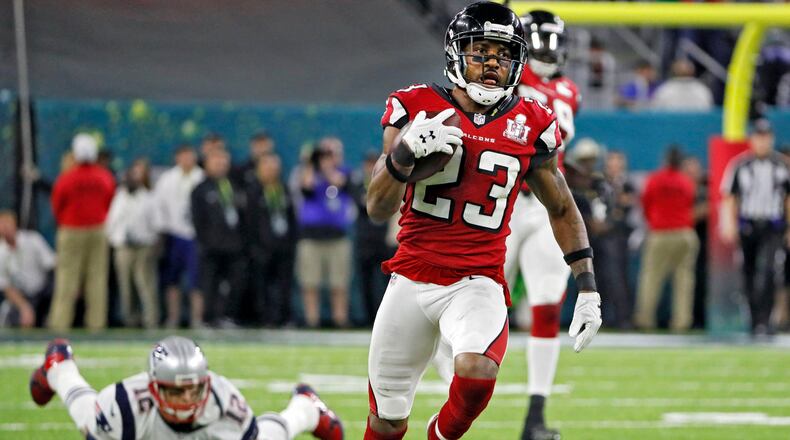 With Patriots quarterback Tom Brady watching in the background, Falcons cornerback Robert Alford heads toward the end zone with an 82-yard interception return that gave the Falcons a 21-0 lead in the second quarter. Bob Andres/AJC