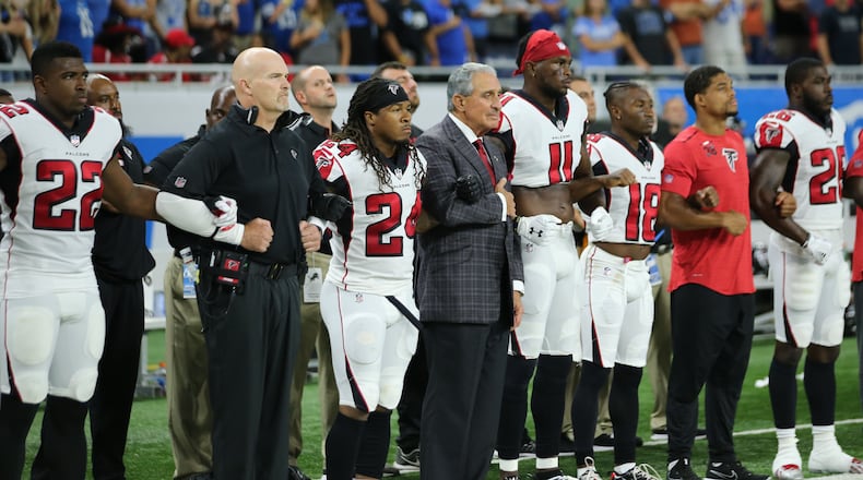 Falcons coach Dan Quinn and team owner Arthur Blank join arms with the players during the playing of the National Anthem prior to Sunday's game at Detroit. (Leon Halip/Getty Images)