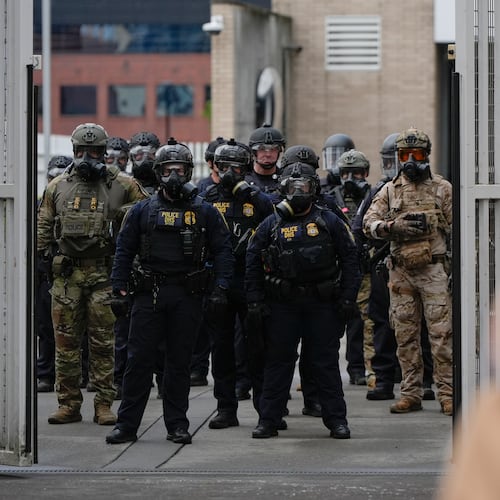 Law enforcement officers watch as the gates close at a U.S. Immigration and Customs Enforcement facility as people protest outside on Saturday, Oct. 11, 2025, in Portland, Ore. (AP Photo/Jenny Kane)