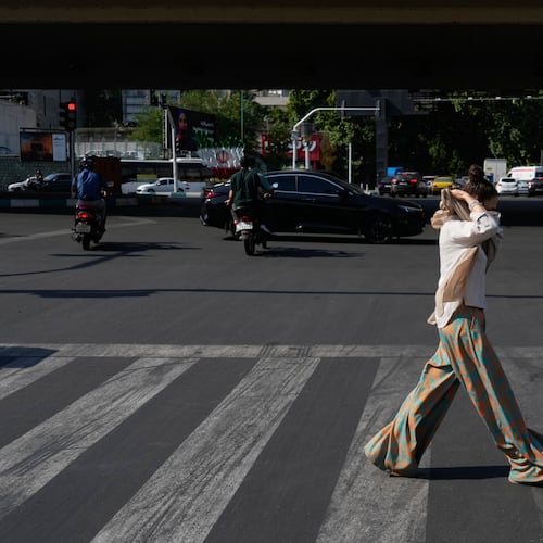 A woman adjusts her headscarf as she crosses an intersection in northern Tehran, Wednesday, June 10, 2026. (AP Photo/Vahid Salemi)