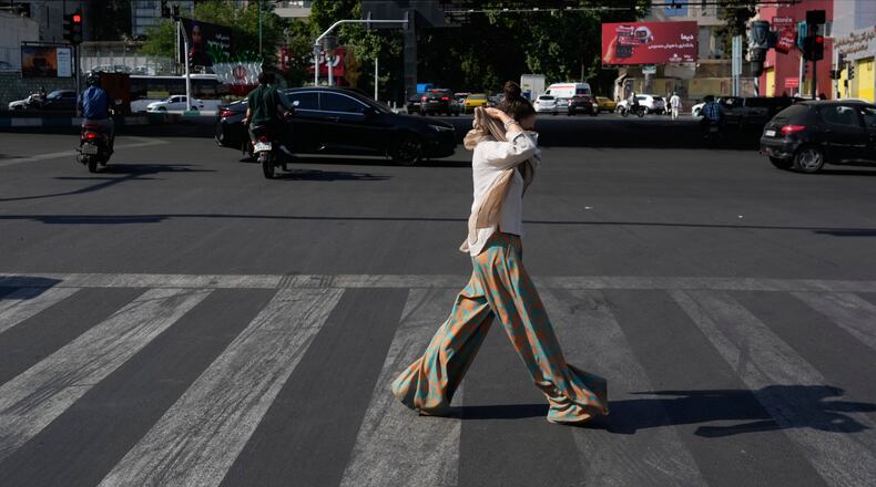 A woman adjusts her headscarf as she crosses an intersection in northern Tehran, Wednesday, June 10, 2026. (AP Photo/Vahid Salemi)