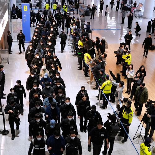 South Koreans, walking in the line at center, who are allegedly involved in online scams in Cambodia, arrive at the Incheon International Airport, in Incheon, South Korea, Friday, Jan. 23, 2026. (AP Photo/Ahn Young-joon)